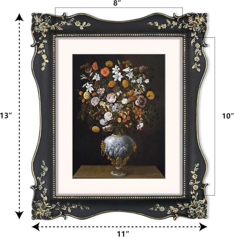 Decorative black picture frame with floral design, containing a painting of flowers in a vase.