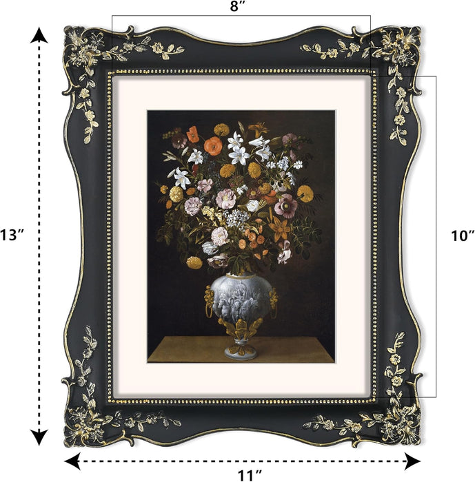 Decorative black picture frame with floral design, containing a painting of flowers in a vase.