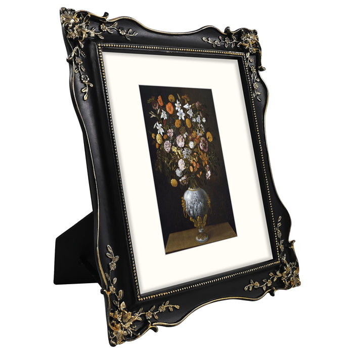 Decorative black frame with gold accents holding a smaller painting of flowers.