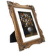 An 8x10 picture frame with floral corner ornaments, designed for tabletop and wall display, made of resin and painted to achieve a vintage look.