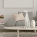 White dog sculpture on a coffee table in a living room setting with a sofa and decorative items.