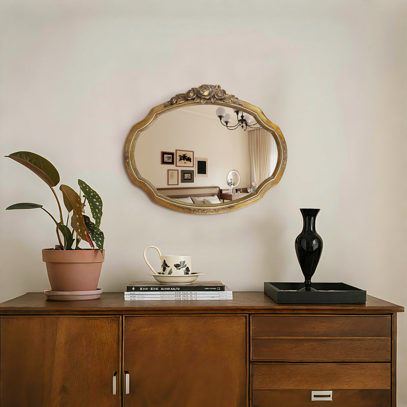 Wooden dresser with decorative items including a plant, books, a vase, and a mirror on a light-colored wall.