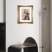 Framed floral painting on a wall with a modern black chair and floor lamp.