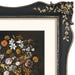 Decorative black and gold frame with floral design, containing a painting of flowers.