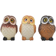A set of three resin owl figurines, painted in different colors, displayed side by side.