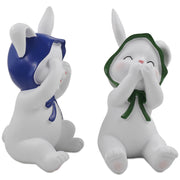 Two resin figurines of sitting rabbits with hats, one with eyes covered and one with a mouth covered, in different poses.
