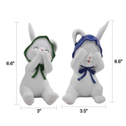 Two resin figurines of sitting rabbits with hats, one with eyes covered and one with a mouth covered, in different poses.