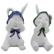Two resin figurines of sitting rabbits with hats, one with eyes covered and one with a mouth covered, in different poses.