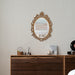 A vintage oval wall mirror with a decorative gold frame, designed for mounting on a wall.