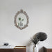 A vintage oval wall mirror with a decorative silver frame, designed for mounting on a wall.
